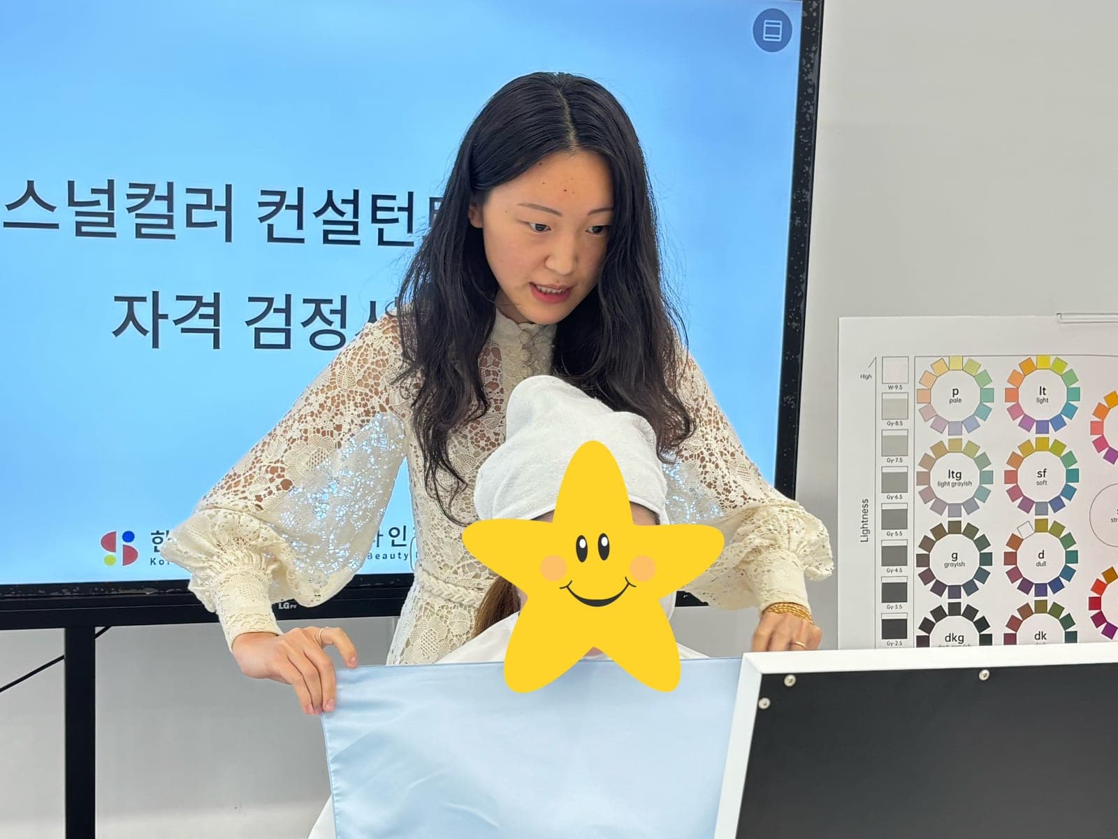 Shanshan draping a fabric next to a client’s face during a color analysis session